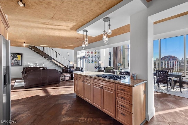 kitchen with a view of city, pendant lighting, stainless steel appliances, open floor plan, and light stone countertops