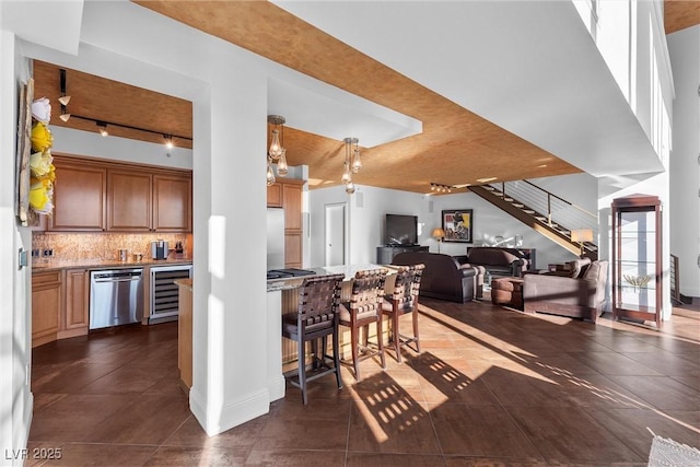 kitchen with wine cooler, tasteful backsplash, appliances with stainless steel finishes, open floor plan, and dark tile patterned floors