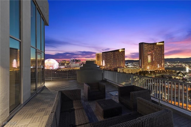 balcony at dusk featuring a view of city