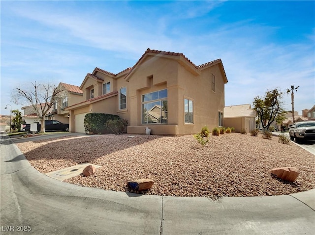 view of front of house with an attached garage, a tiled roof, concrete driveway, and stucco siding