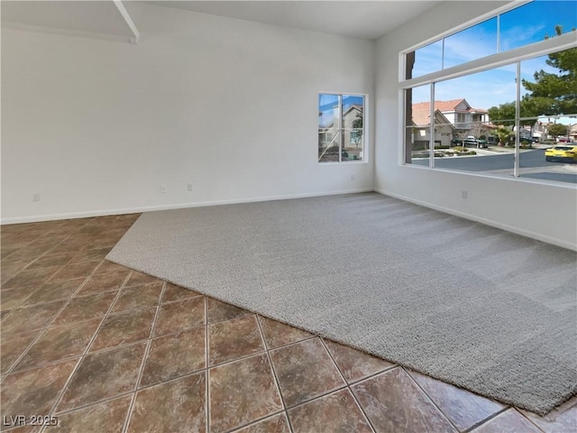 carpeted spare room with baseboards and tile patterned floors