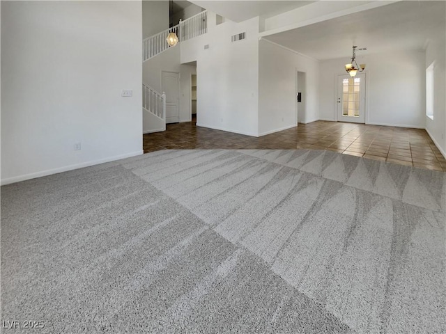 carpeted spare room with tile patterned flooring, visible vents, baseboards, stairs, and an inviting chandelier