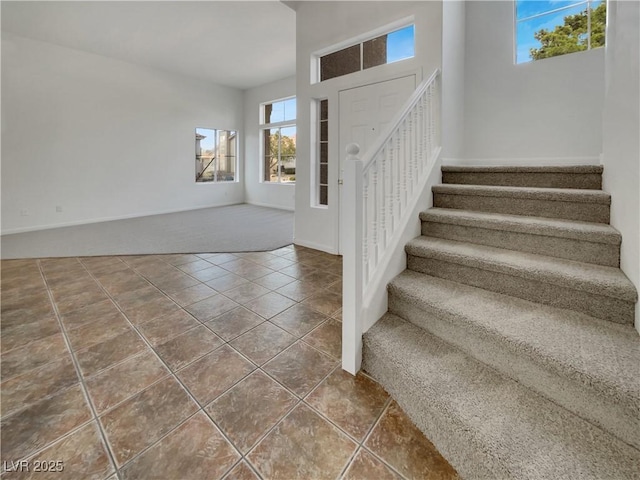 foyer with tile patterned flooring, baseboards, and stairs