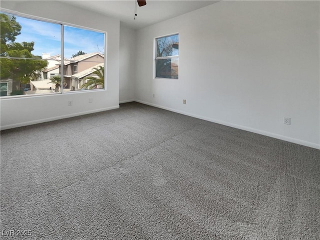 carpeted empty room with a ceiling fan and baseboards