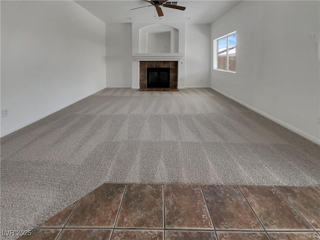 unfurnished living room featuring ceiling fan, baseboards, a tiled fireplace, and carpet flooring