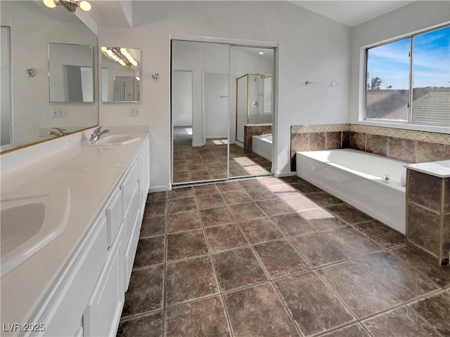 bathroom featuring a garden tub, a sink, a shower stall, and double vanity