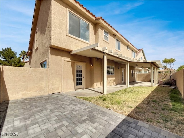 rear view of house with a fenced backyard, a tiled roof, a patio, and stucco siding