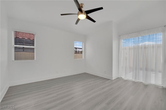 empty room featuring wood finished floors, a ceiling fan, and baseboards