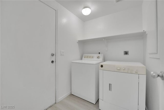 clothes washing area with light wood-style flooring, laundry area, and washer and clothes dryer