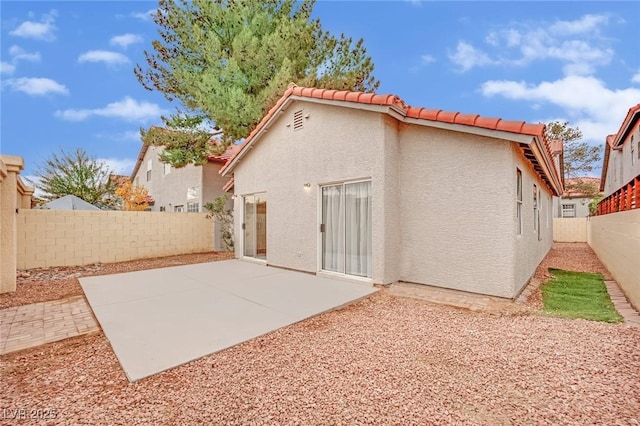 back of house featuring a patio area, a fenced backyard, a tile roof, and stucco siding