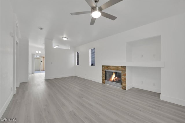 unfurnished living room featuring light wood-type flooring, a warm lit fireplace, and baseboards