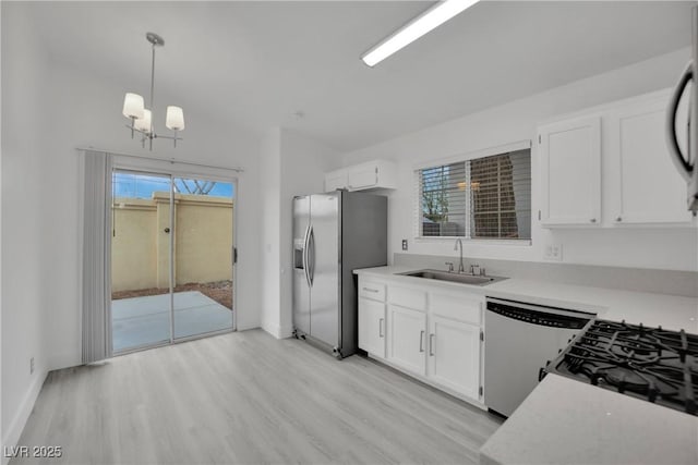 kitchen featuring stainless steel appliances, a sink, white cabinetry, light countertops, and light wood-type flooring