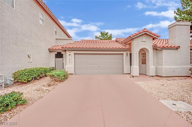 mediterranean / spanish home featuring a garage, driveway, a tile roof, and stucco siding