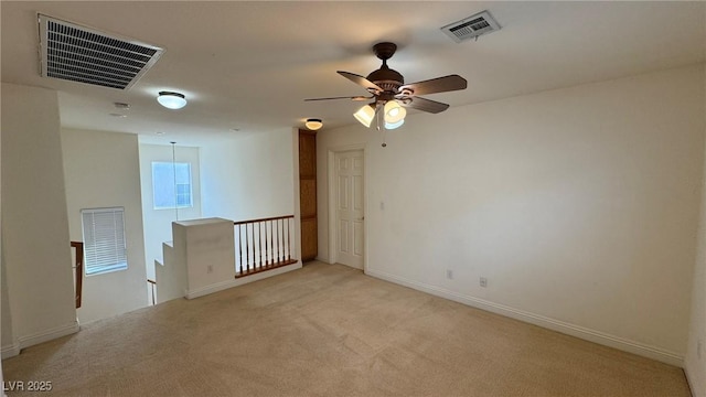 spare room featuring visible vents, ceiling fan, light carpet, and baseboards