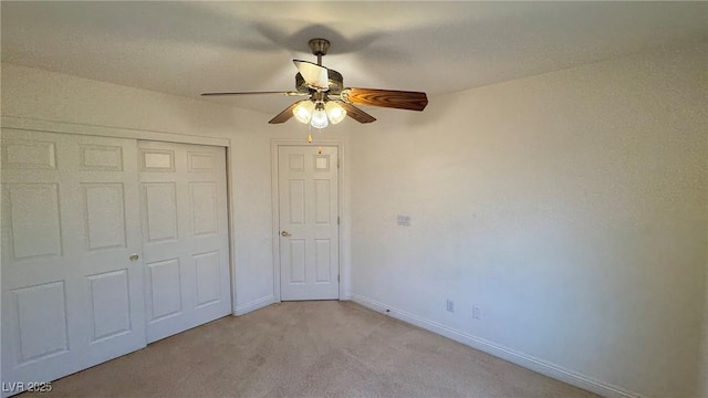 unfurnished bedroom with light carpet, ceiling fan, baseboards, and a closet