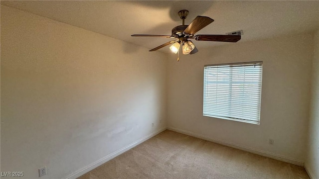 empty room featuring light carpet, ceiling fan, visible vents, and baseboards