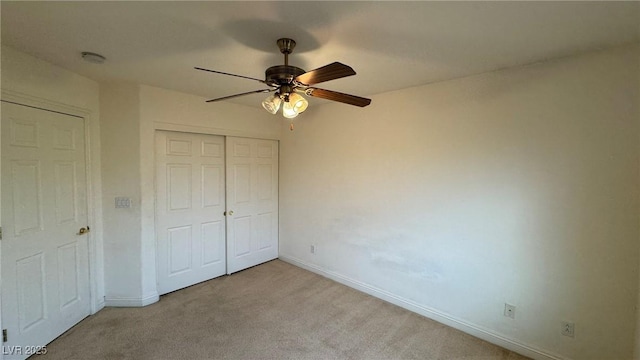 unfurnished bedroom featuring a ceiling fan, a closet, light carpet, and baseboards