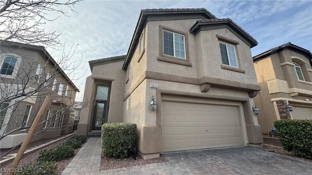 view of front of house featuring an attached garage, a tiled roof, decorative driveway, and stucco siding