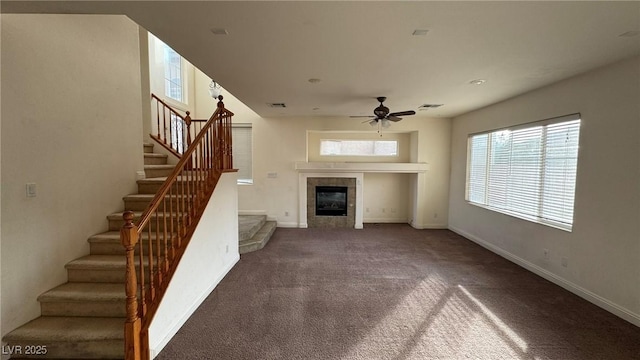 unfurnished living room featuring ceiling fan, carpet, baseboards, stairs, and a tiled fireplace