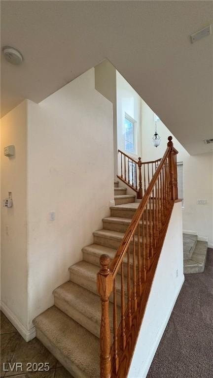 staircase with visible vents and baseboards