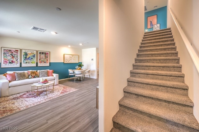 stairs with wood finished floors, visible vents, and baseboards