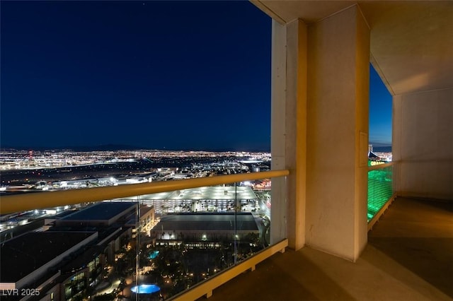 balcony at night featuring a view of city lights