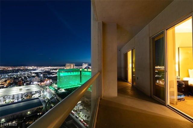 balcony at night featuring a view of city lights