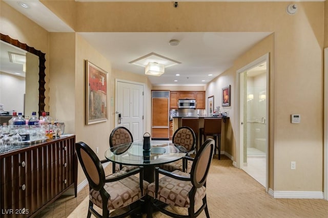 dining room with recessed lighting, a dry bar, and baseboards