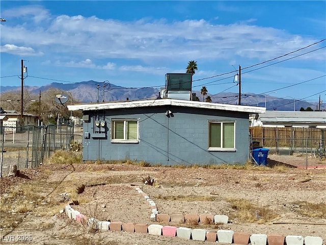 rear view of house featuring concrete block siding, fence, and a mountain view