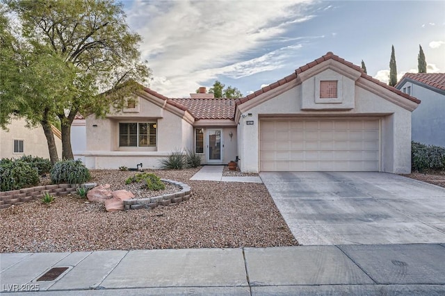 mediterranean / spanish home featuring an attached garage, a tiled roof, concrete driveway, and stucco siding