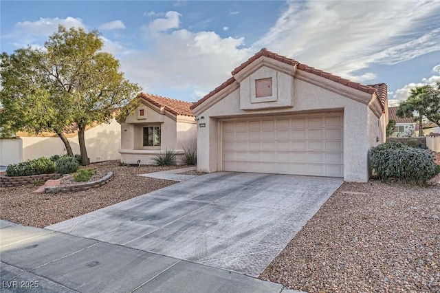 mediterranean / spanish home featuring a garage, a tile roof, concrete driveway, and stucco siding