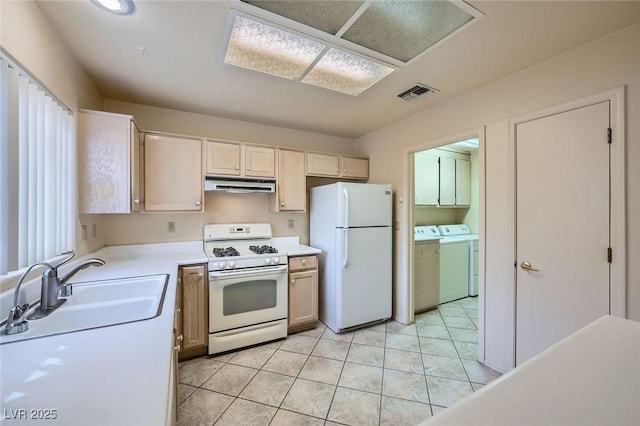 kitchen featuring white appliances, visible vents, washing machine and clothes dryer, under cabinet range hood, and a sink