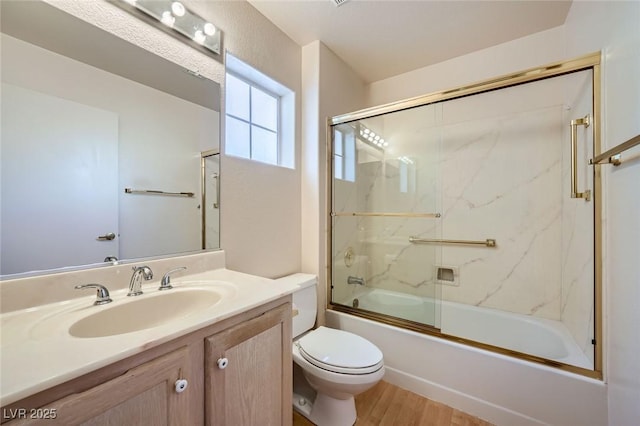 bathroom with enclosed tub / shower combo, wood finished floors, vanity, and toilet