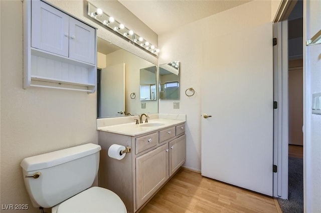 bathroom with toilet, wood finished floors, and vanity