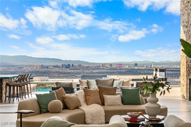 view of patio featuring a balcony, an outdoor hangout area, a view of city, and a mountain view
