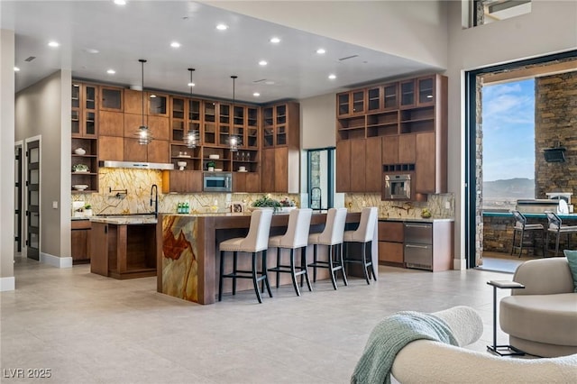 kitchen featuring open floor plan, open shelves, a kitchen breakfast bar, and a center island with sink