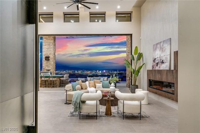 living room with ceiling fan and a glass covered fireplace