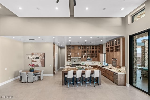 kitchen with modern cabinets, a kitchen bar, recessed lighting, a spacious island, and backsplash