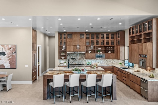 kitchen with a spacious island, a sink, a breakfast bar, appliances with stainless steel finishes, and decorative backsplash