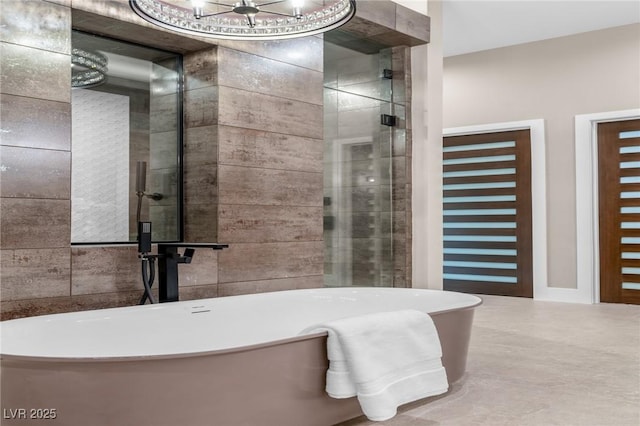bathroom with a freestanding tub, a notable chandelier, tiled shower, and tile walls