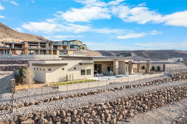 back of property with stucco siding, a mountain view, and fence