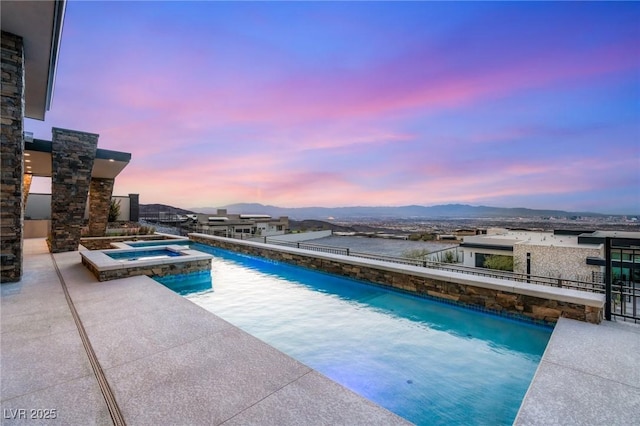 view of swimming pool with a mountain view, a pool with connected hot tub, and a patio area
