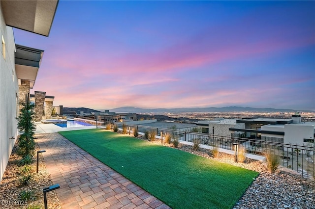 exterior space with a pool with connected hot tub, a fenced backyard, a lawn, a mountain view, and a patio area