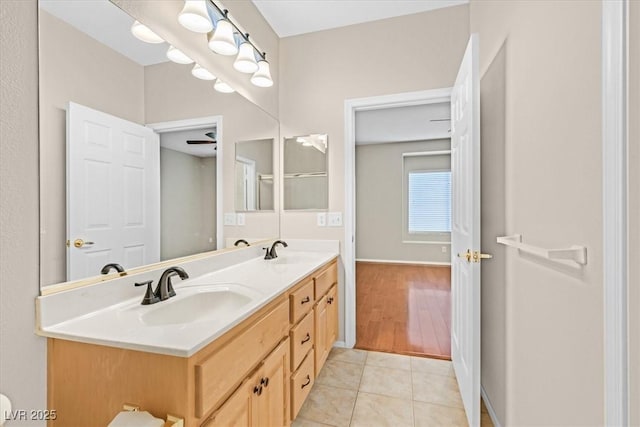 bathroom featuring tile patterned flooring, a sink, baseboards, and double vanity