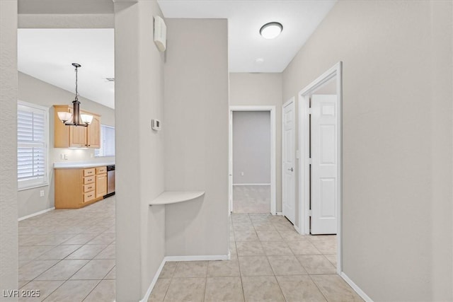 hallway featuring light tile patterned floors, an inviting chandelier, and baseboards