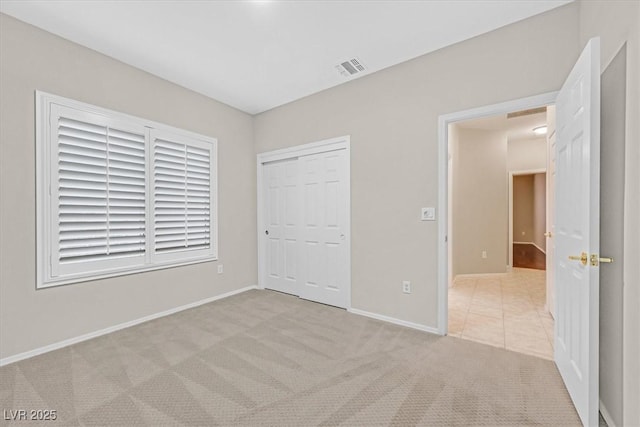 unfurnished bedroom with baseboards, a closet, visible vents, and light colored carpet