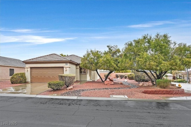 view of front of home featuring driveway, an attached garage, a tiled roof, and stucco siding