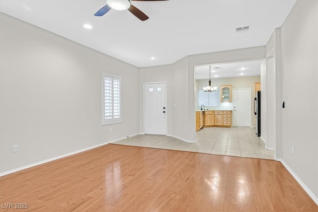 foyer entrance with light wood finished floors, visible vents, baseboards, ceiling fan with notable chandelier, and recessed lighting