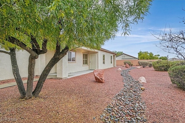 rear view of house featuring fence, a patio, and stucco siding