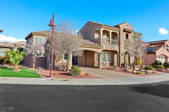 mediterranean / spanish home featuring stucco siding, fence, a balcony, driveway, and a tiled roof